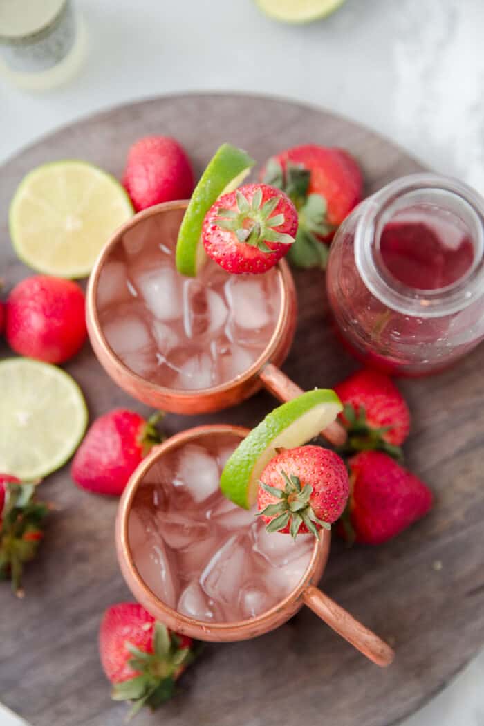 two moscow mules with strawberries and limes