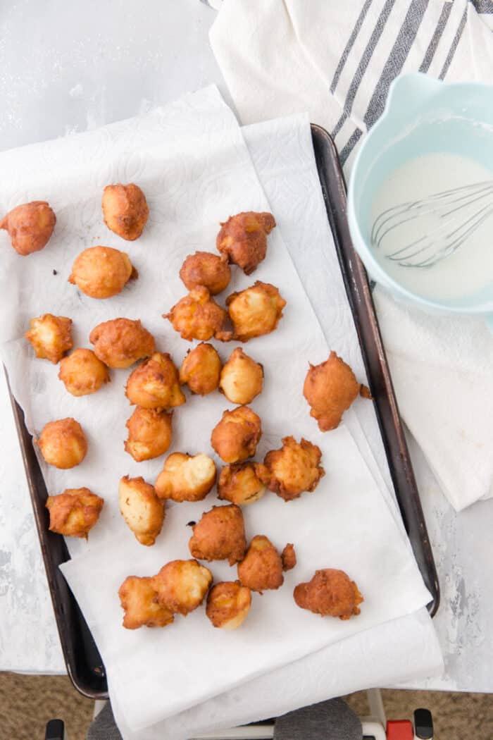 fried fritters draining on a baking sheet