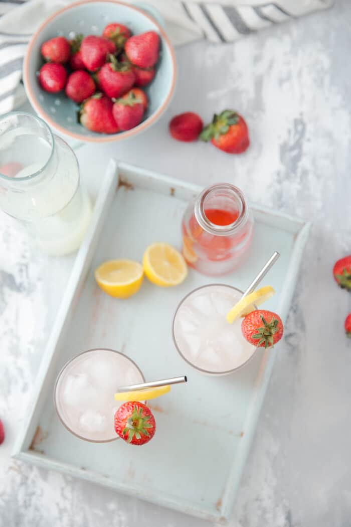 vodka lemonade glasses on a blue tray with strawberries on the side