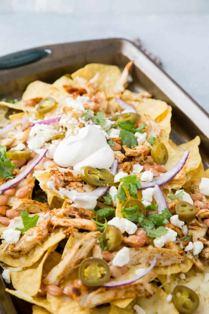 pan of nachos with toppings and white bbq sauce 