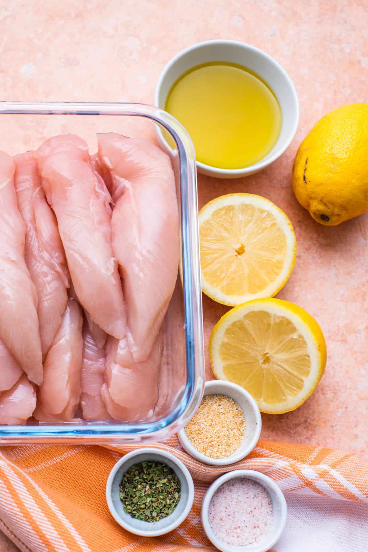 raw strips of chicken seasonings sliced lemon and olive oil