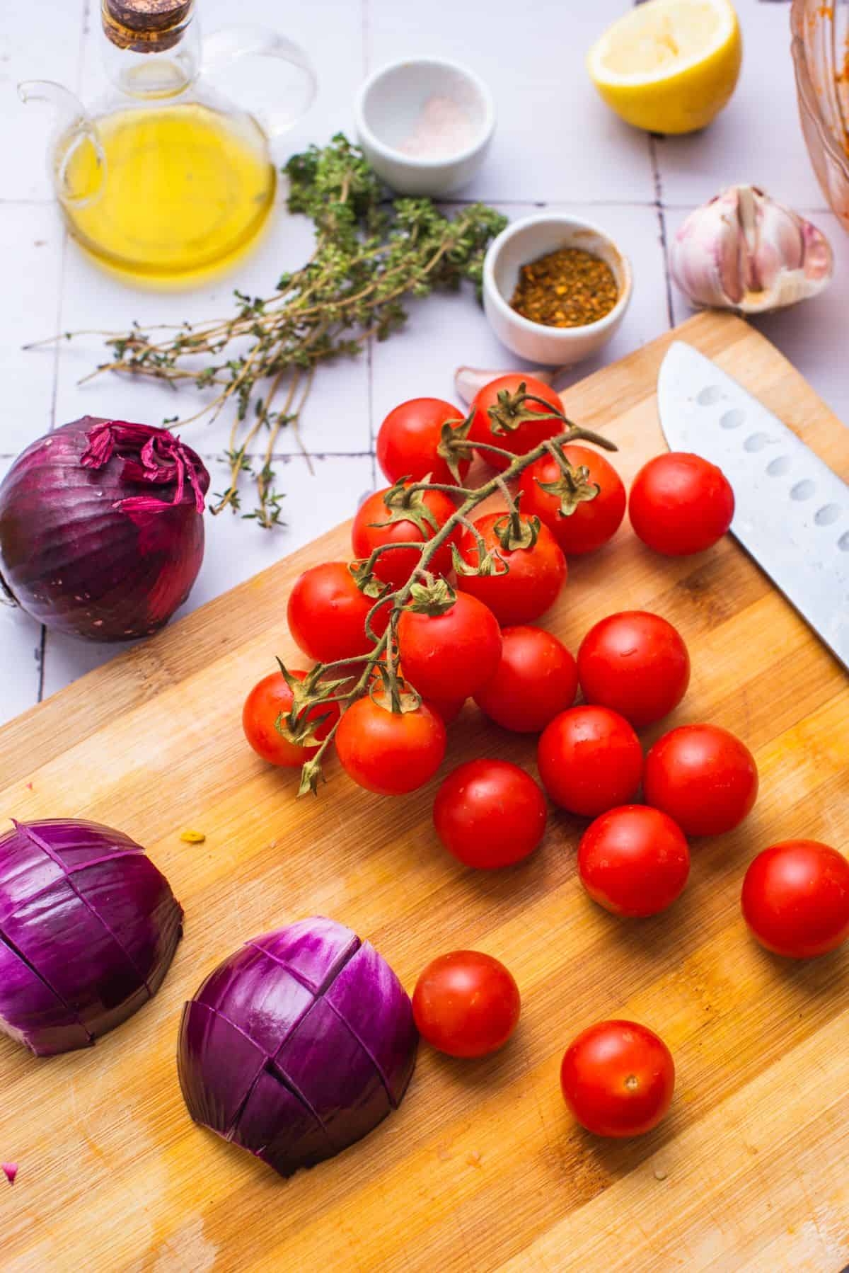 cherry tomatoes and red onion on cutting board