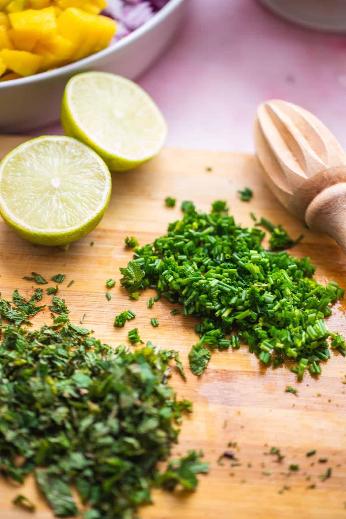 chopped chives and mint with lemon halves on cutting board