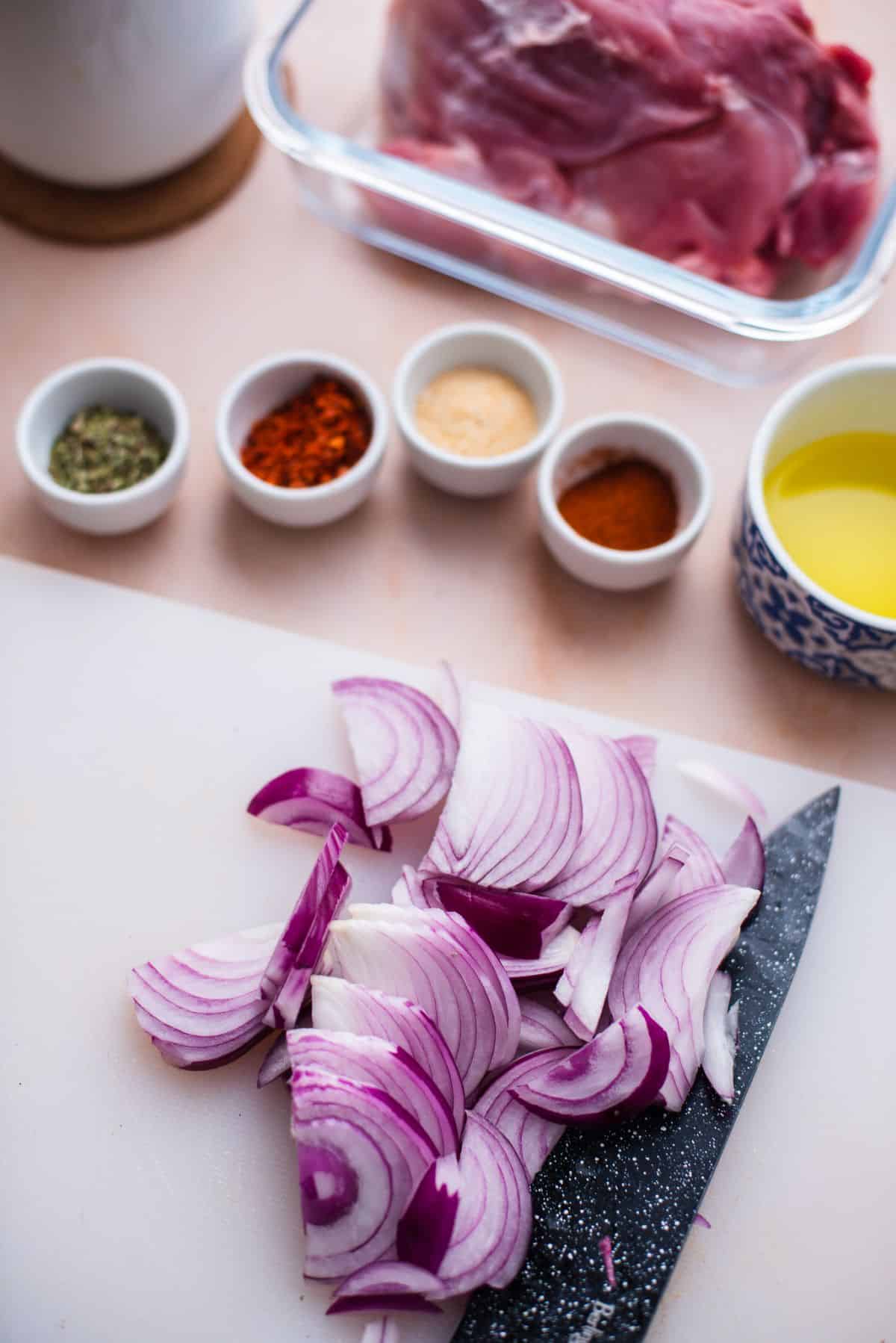chopped red onion on cutting board and seasonings