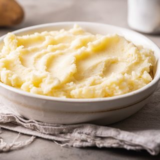 Mashed potatoes become a loaded casserole with sour cream, bacon, green onions, and three cups of cheddar. Assemble it a day ahead, then bake when dinner needs it.